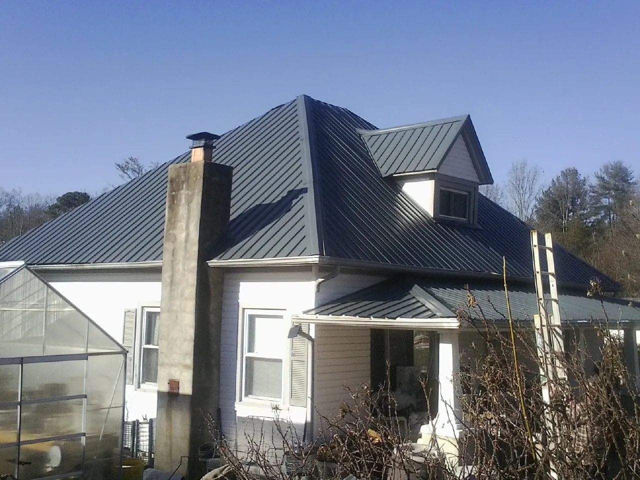 Dark blue standing seam metal roof on a white farmhouse with dormer — Slate & Tile Roof Repair by Roofing Brothers in Miamitown