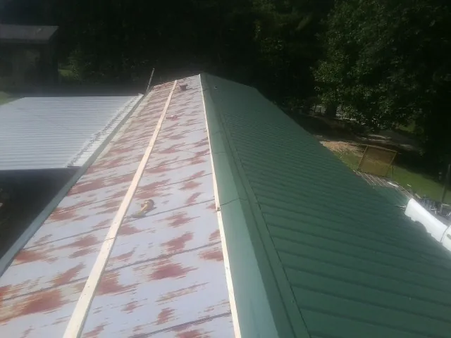 Old rusted panels beside newly installed green metal roofing — Wind Damage Roof Repair by Roofing Brothers in Miamitown