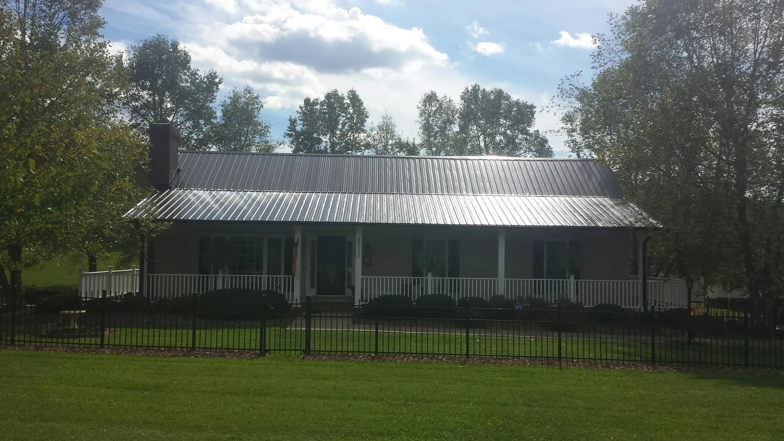 Gray metal roof on a brick ranch with a full width front porch — Gutter Guard Installation work by our crew in Miamitown