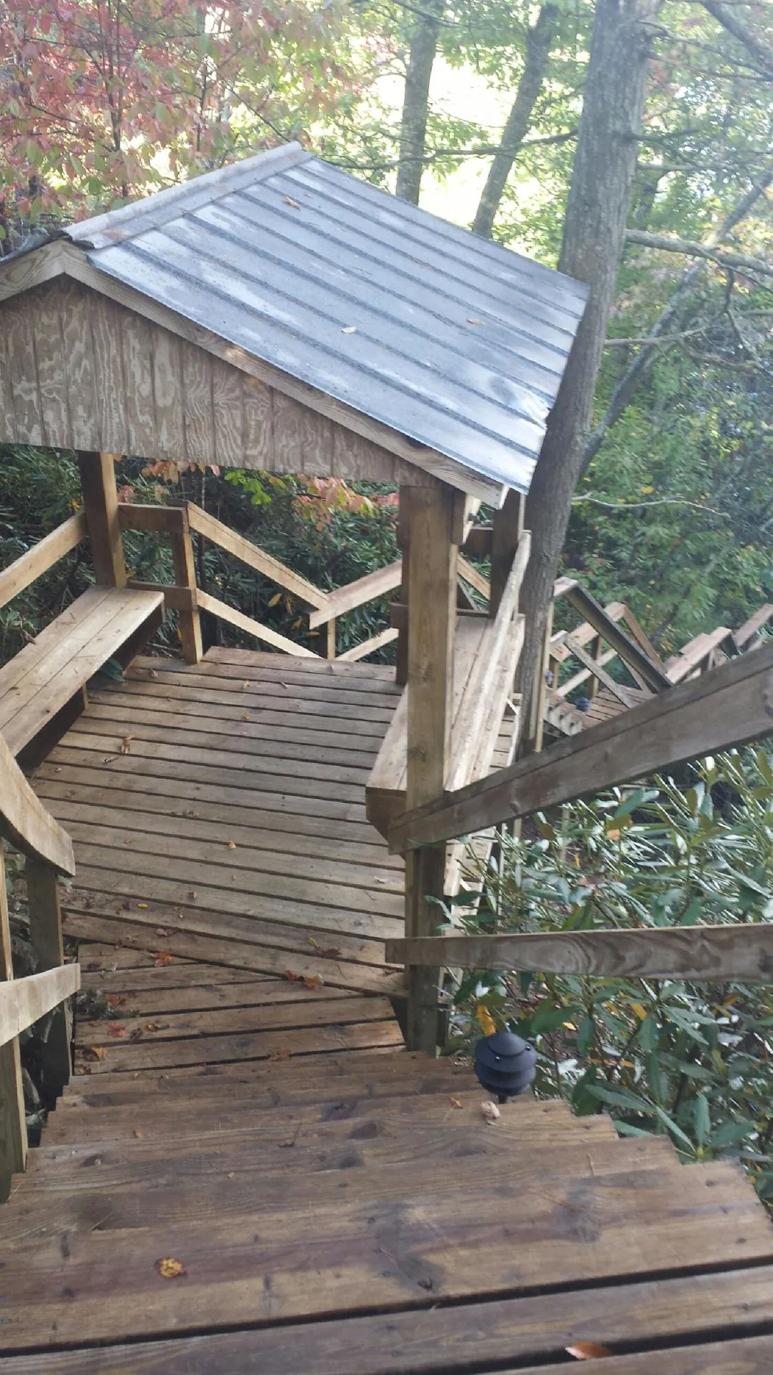 Metal roofed shelter over wooden steps on a wooded walkway — Skylight Repair & Installation work by our crew in Miamitown