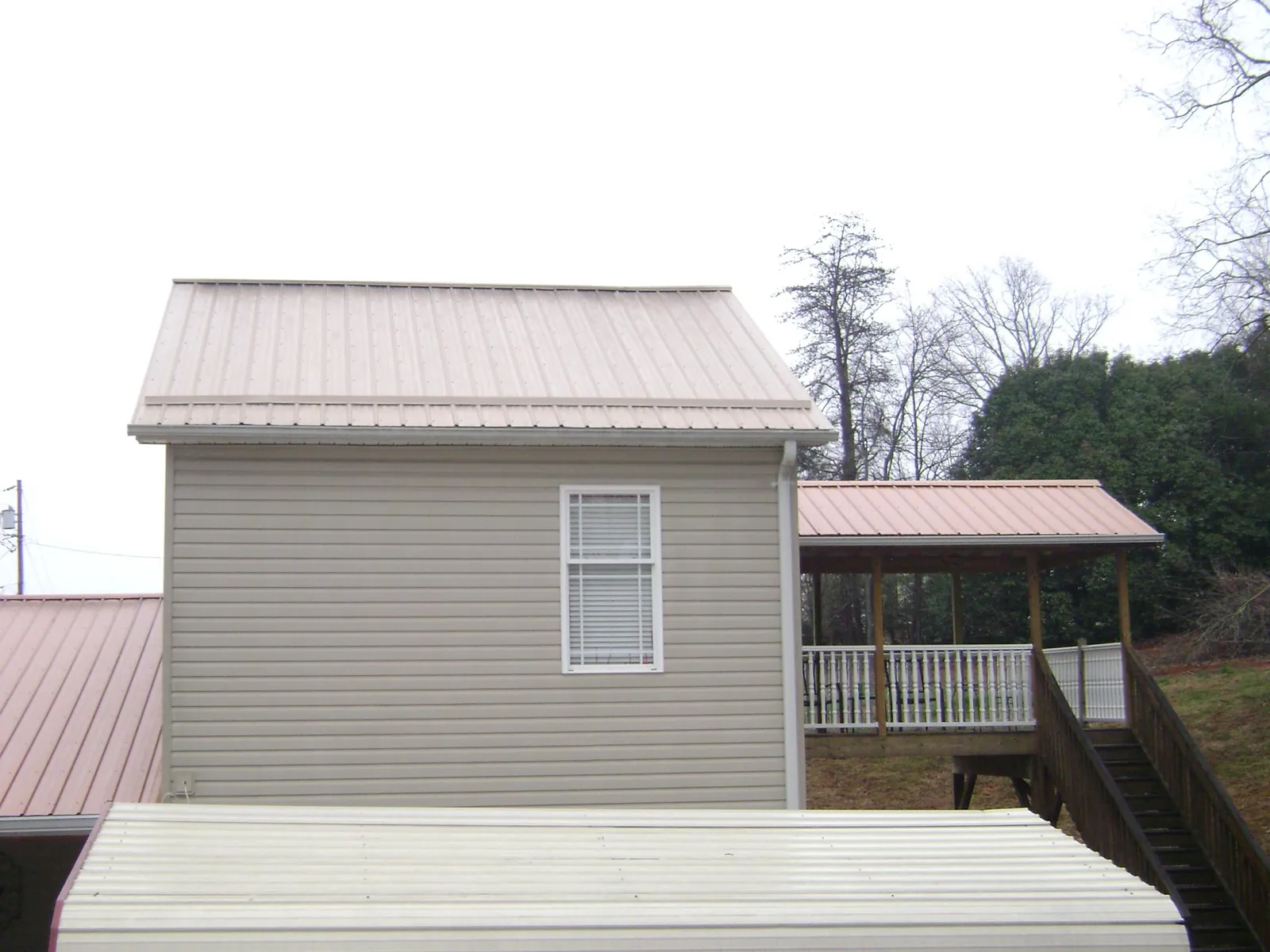Tan metal roofs on a two story addition and attached porch, from a Roof Replacement job in Miamitown