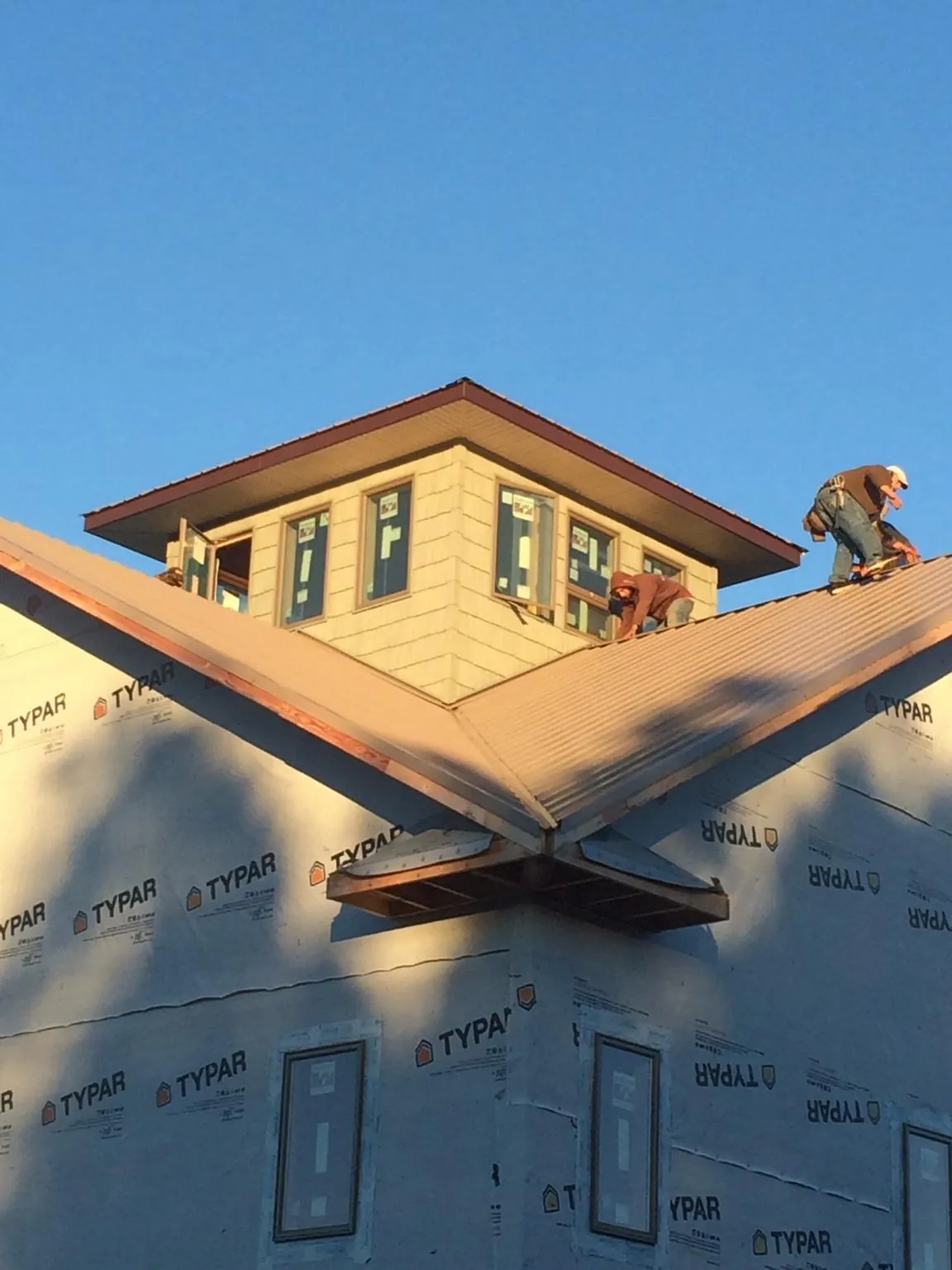 Roofers working around a rooftop cupola on a new metal roof at sunset — Roof Waterproofing in Miamitown by Roofing Brothers